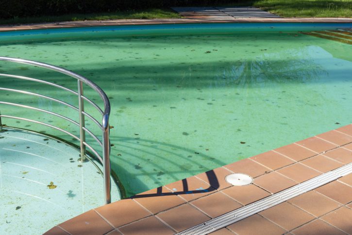 Dirty swimming pool with leaves in the pool bottom. Cleaning con