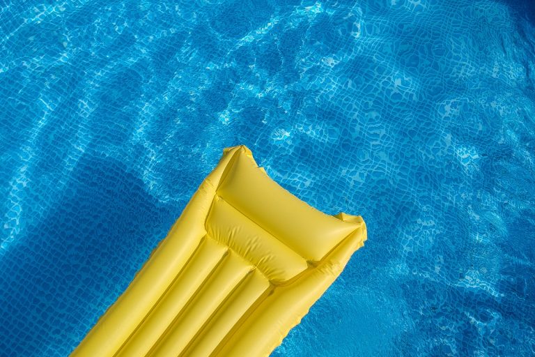 Top view of an inflatable mattress in a backyard swimming pool
