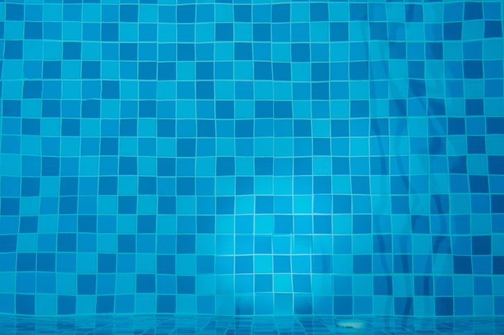 Blue clear water of swimming pool with mosaic bottom. Top view.